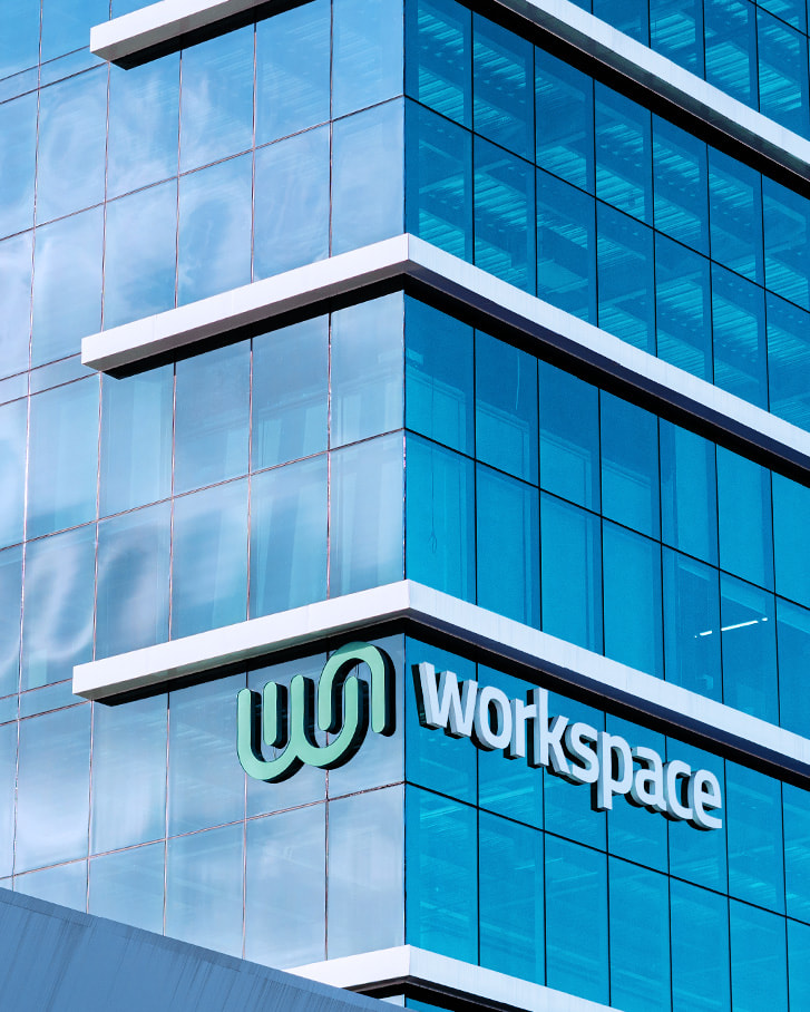 Close up of glass building with extruded logo signage of Worskspace horizontal logo