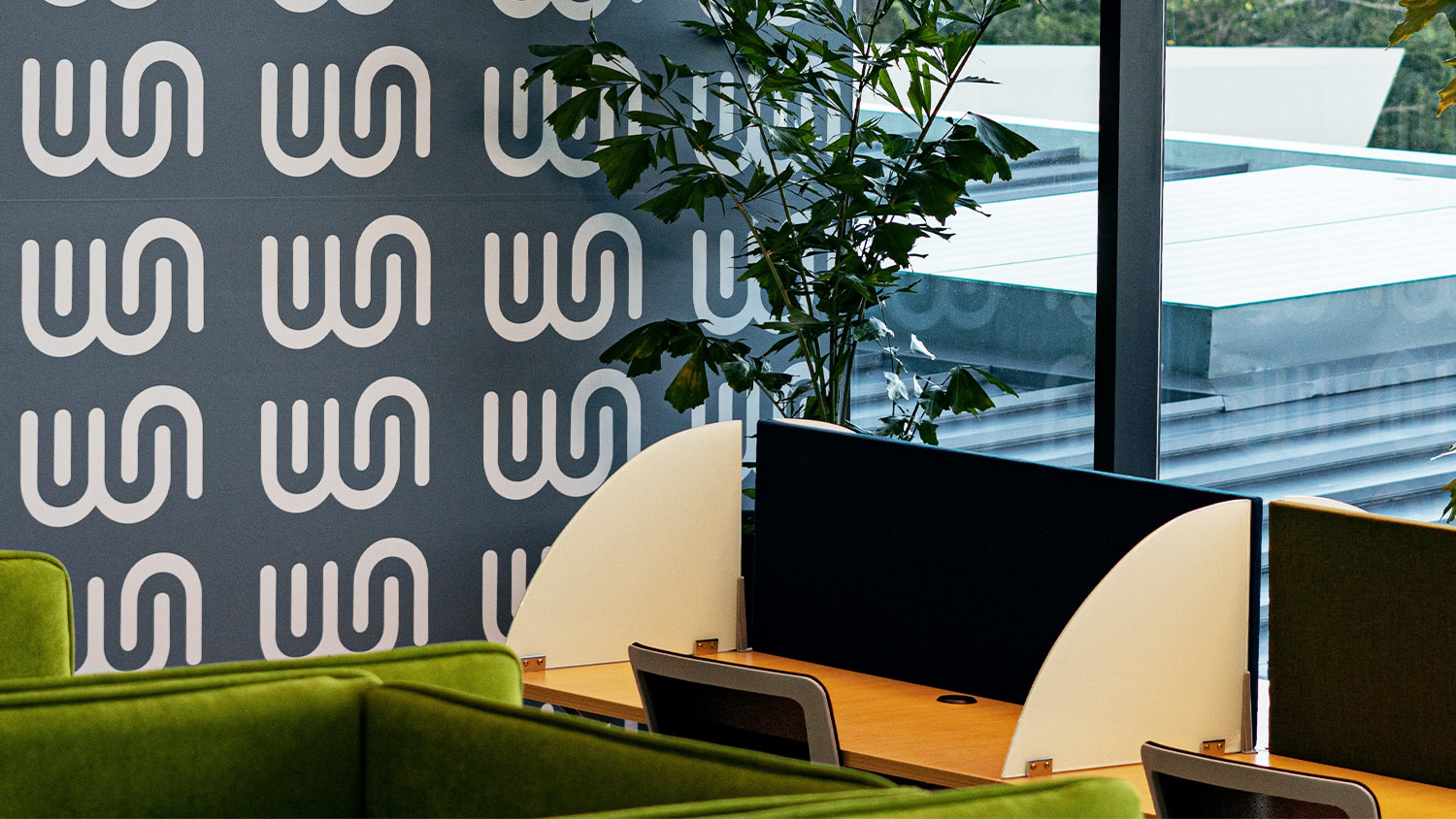 Inside of Workspace office space showing desks setupand the logo pattern on the wall