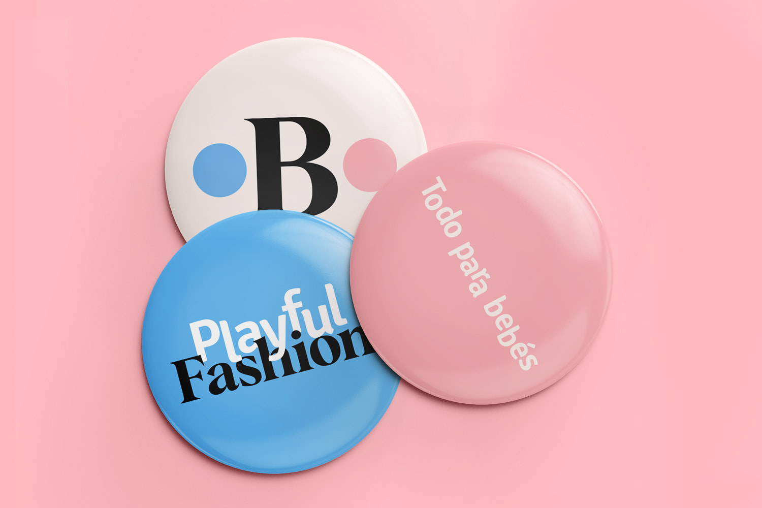 Three Babymania button designs: one with logo icon, one blue one with a phrase, and one pink one with the brand slogan