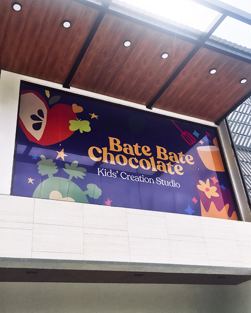 Exterior window signage design with the logotype of Bate Bate Chocolate and fun childlike cutout illustrations